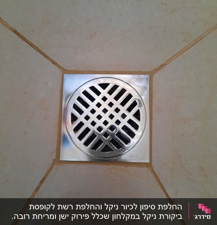 פתח ניקוז מתכת מרובע על רצפת אריחים